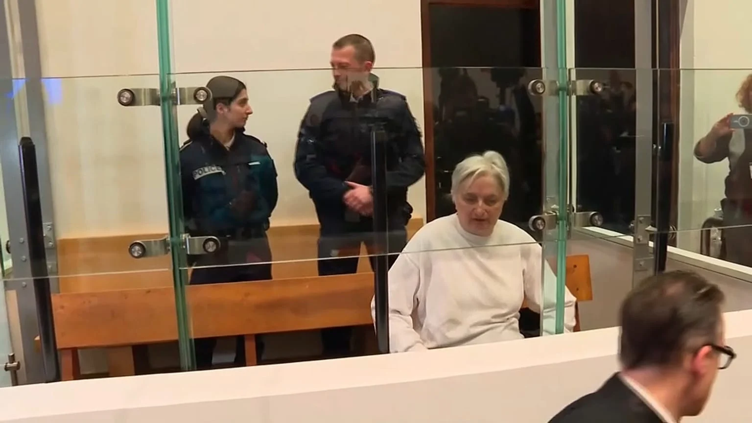 Monique Olivier, white-haired, seated in the glass dock of a French courtroom