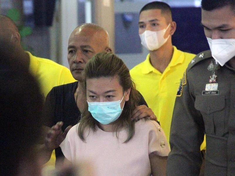 Sararat Rangsiwuthaporn, wearing a face mask, led by Thai police officers