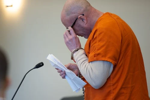 Sean Lannon, in an orange jail uniform, reading from a paper in court