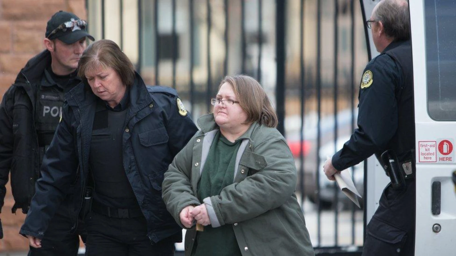 Elizabeth Wettlaufer in a green coat, escorted by police officers