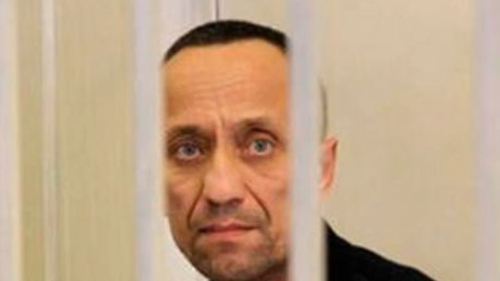 Mikhail Popkov behind the bars of a defendants' cage in a Russian courtroom