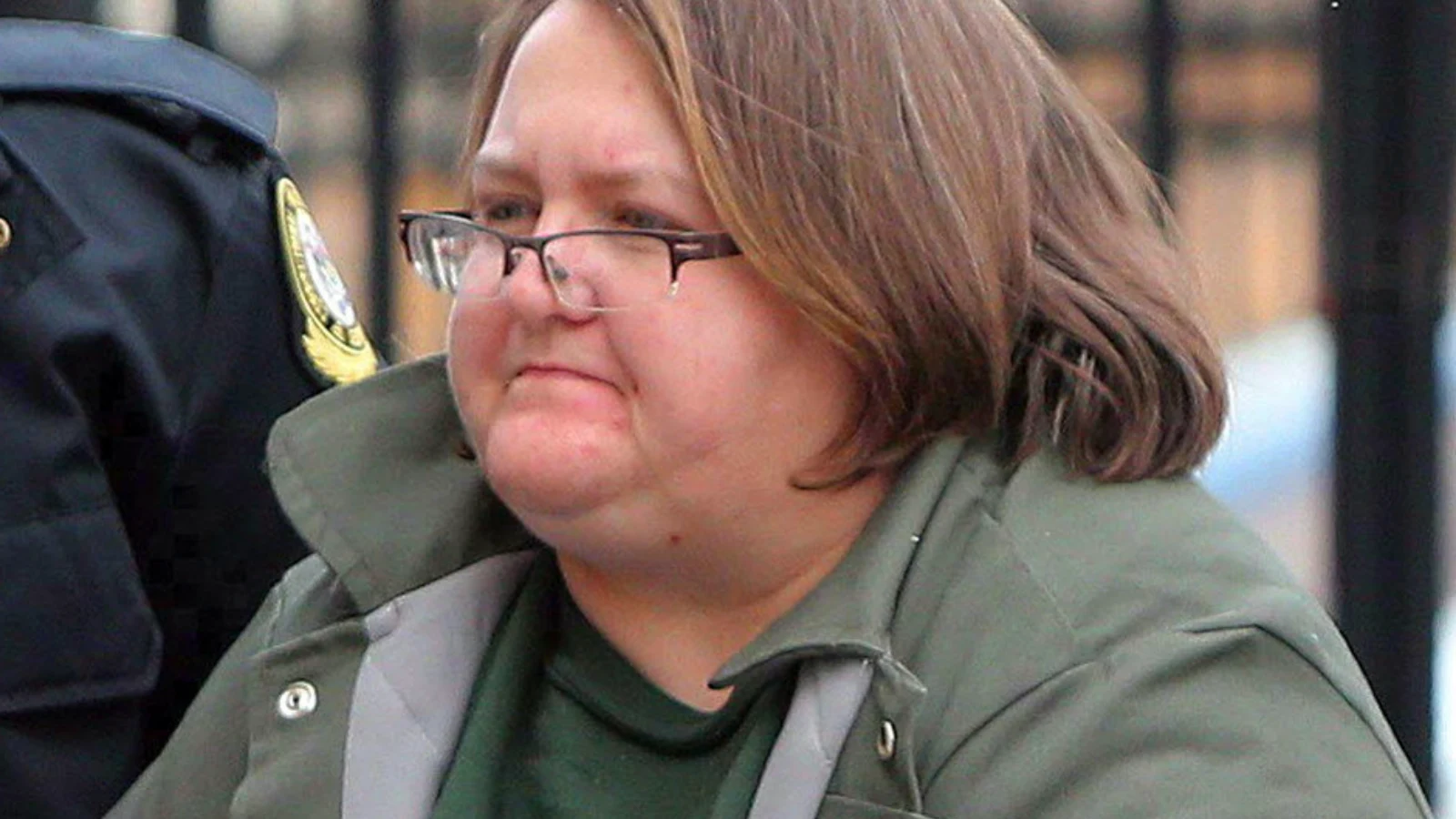 Elizabeth Wettlaufer, in glasses and a green jacket, escorted by police outside court