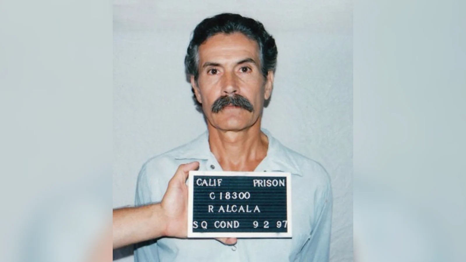 Rodney Alcala in a 1997 San Quentin condemned-row booking photograph, holding a prison name board