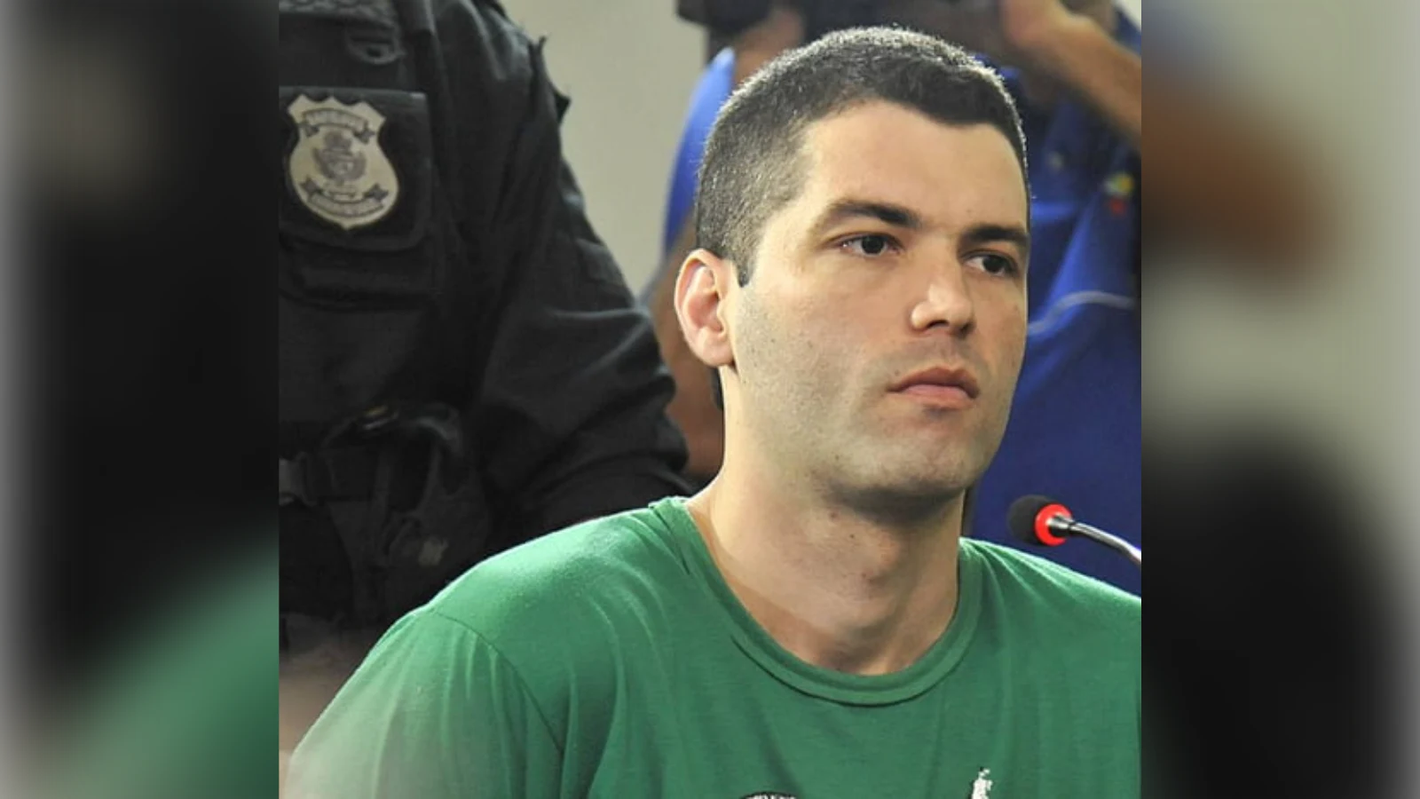 Tiago Henrique Gomes da Rocha in a green T-shirt in court, with a police officer behind him