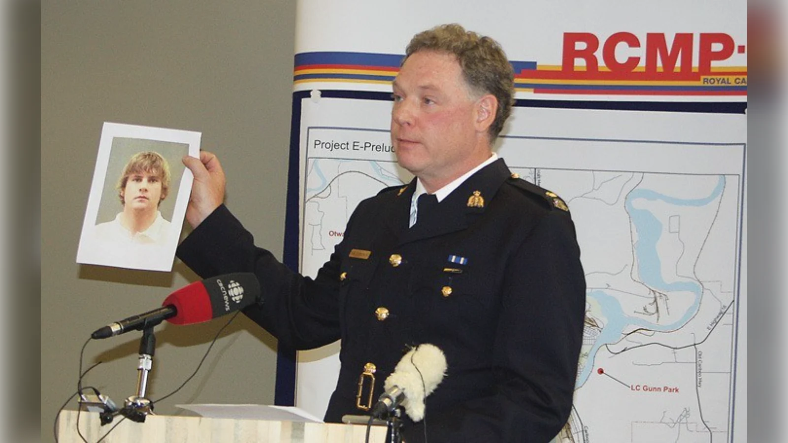 An RCMP officer holds up a photograph of Cody Legebokoff at a police news conference in Prince George