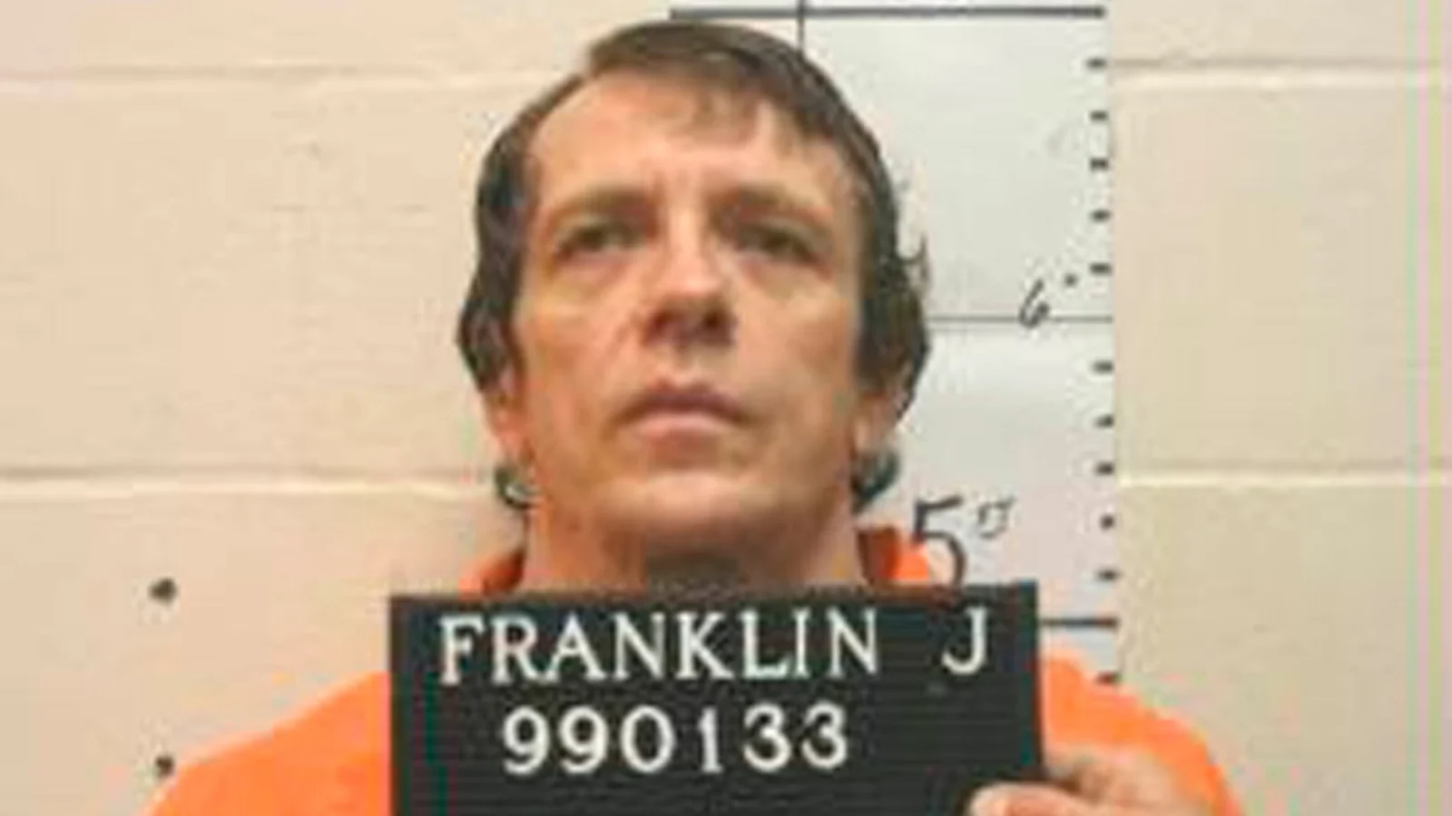 Joseph Paul Franklin in an orange prison uniform holding a Missouri Department of Corrections placard