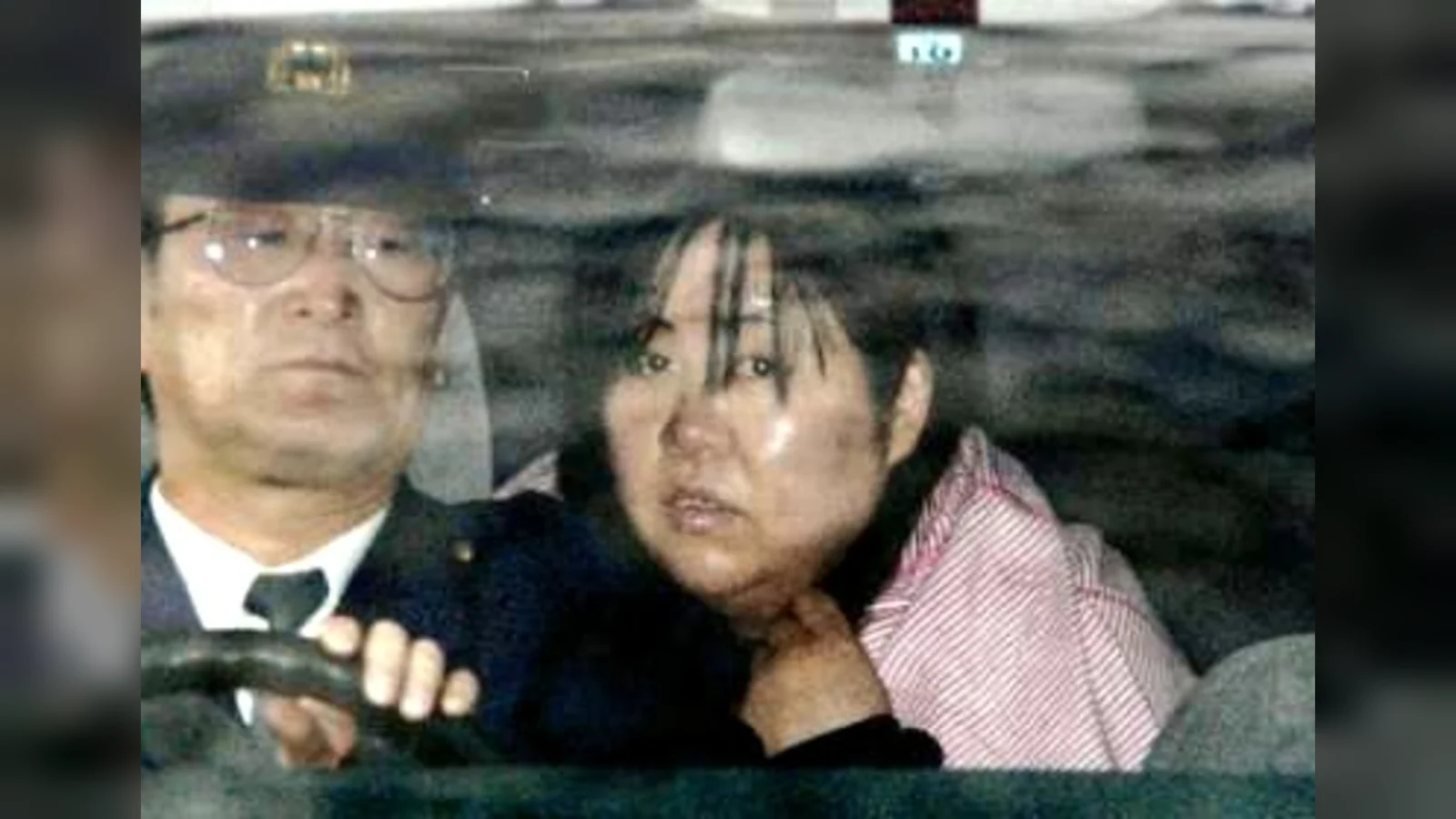 Kanae Kijima in the back of a police car beside an officer