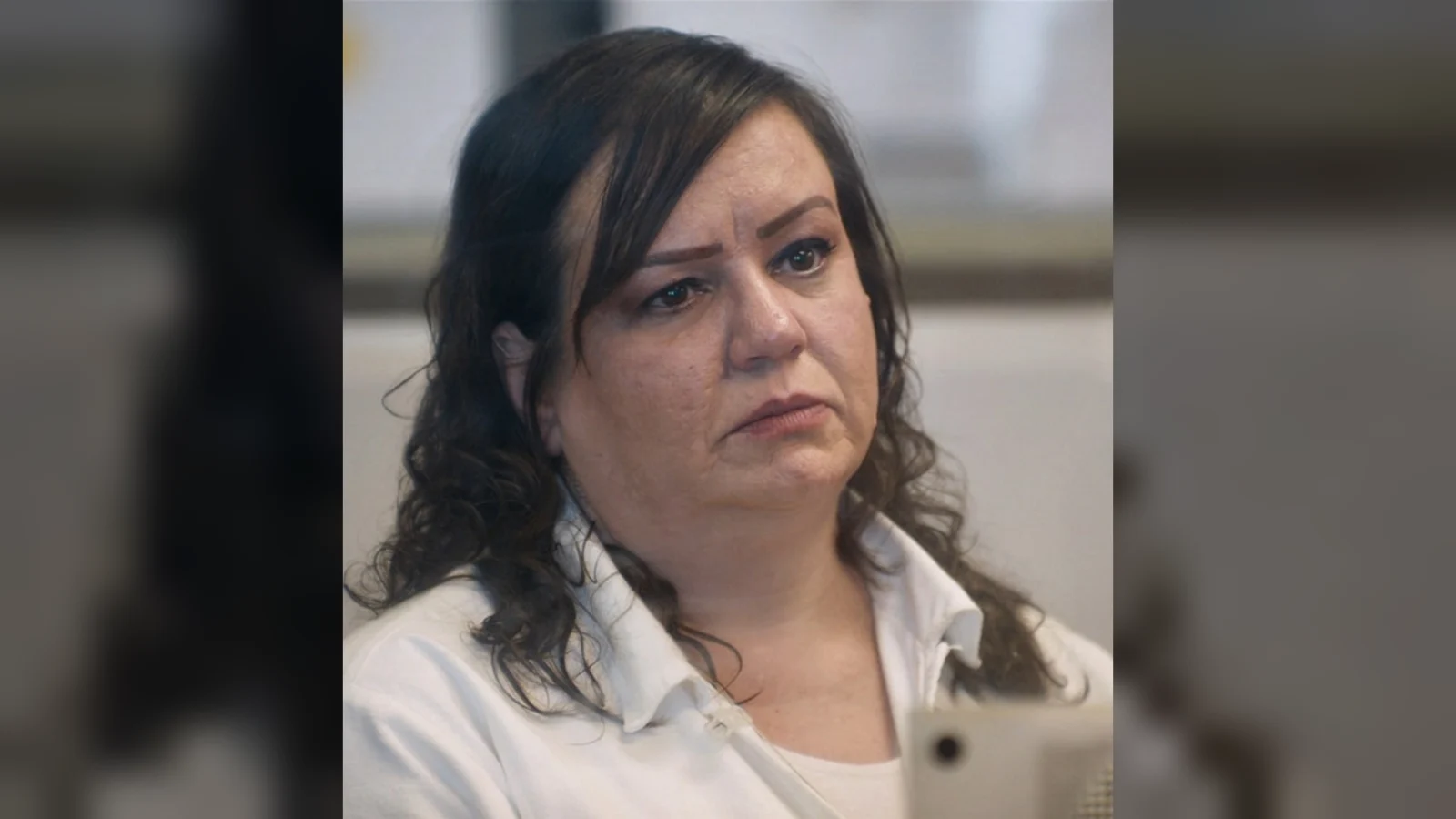Kimberly Clark Saenz in a white blouse, seated and looking ahead