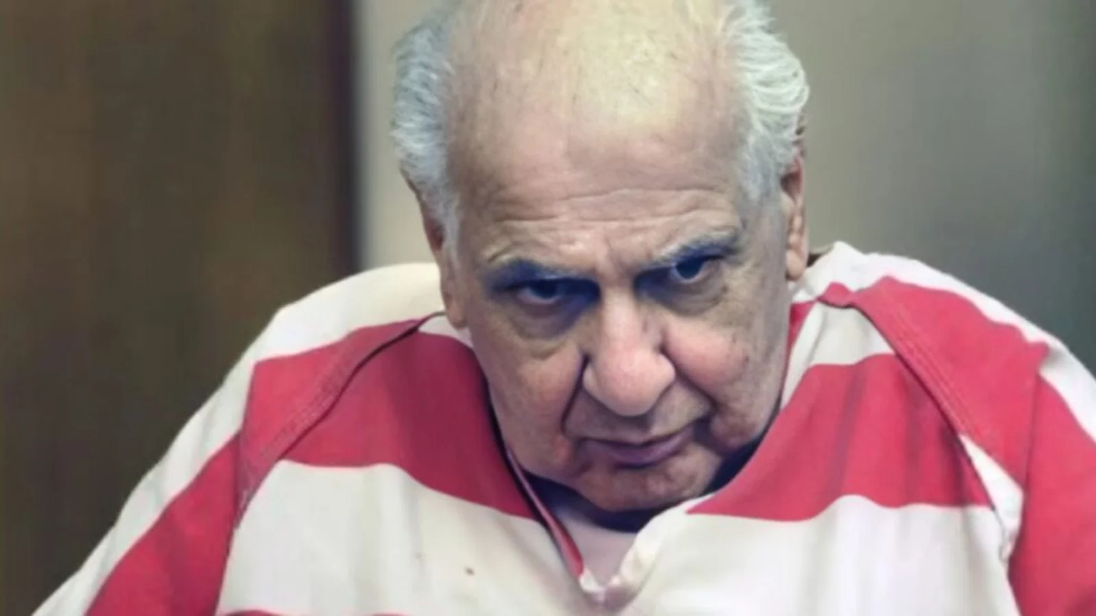 Joseph Naso, white-haired, in a red-and-white striped jail shirt in court