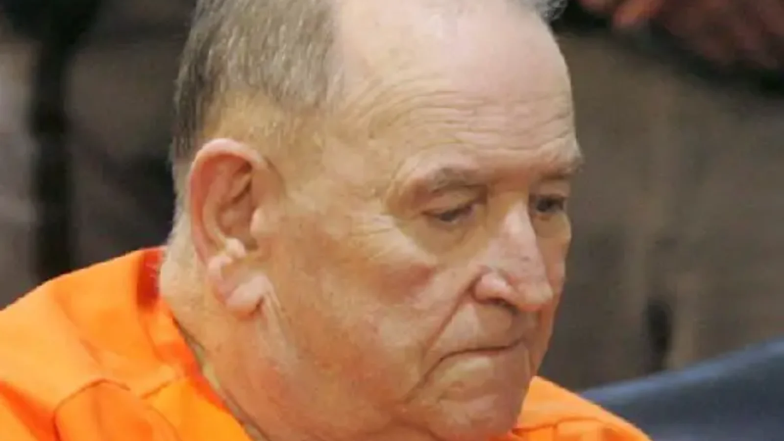 Edward Wayne Edwards, elderly, in an orange jail jumpsuit in court, looking down