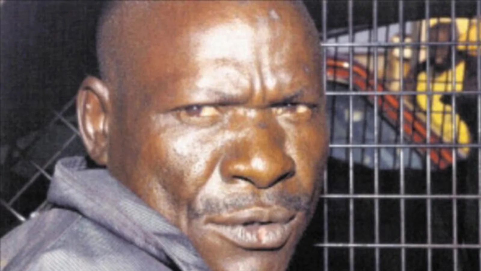 Jack Mogale in a gray hooded top beside a mesh grille, looking at the camera
