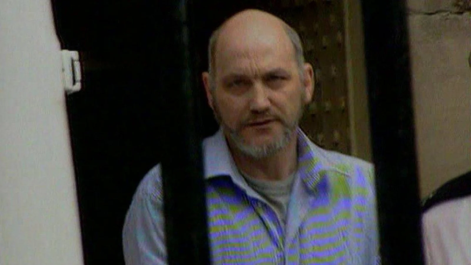 Robert Black, bearded, seen through the barred door of a prison van
