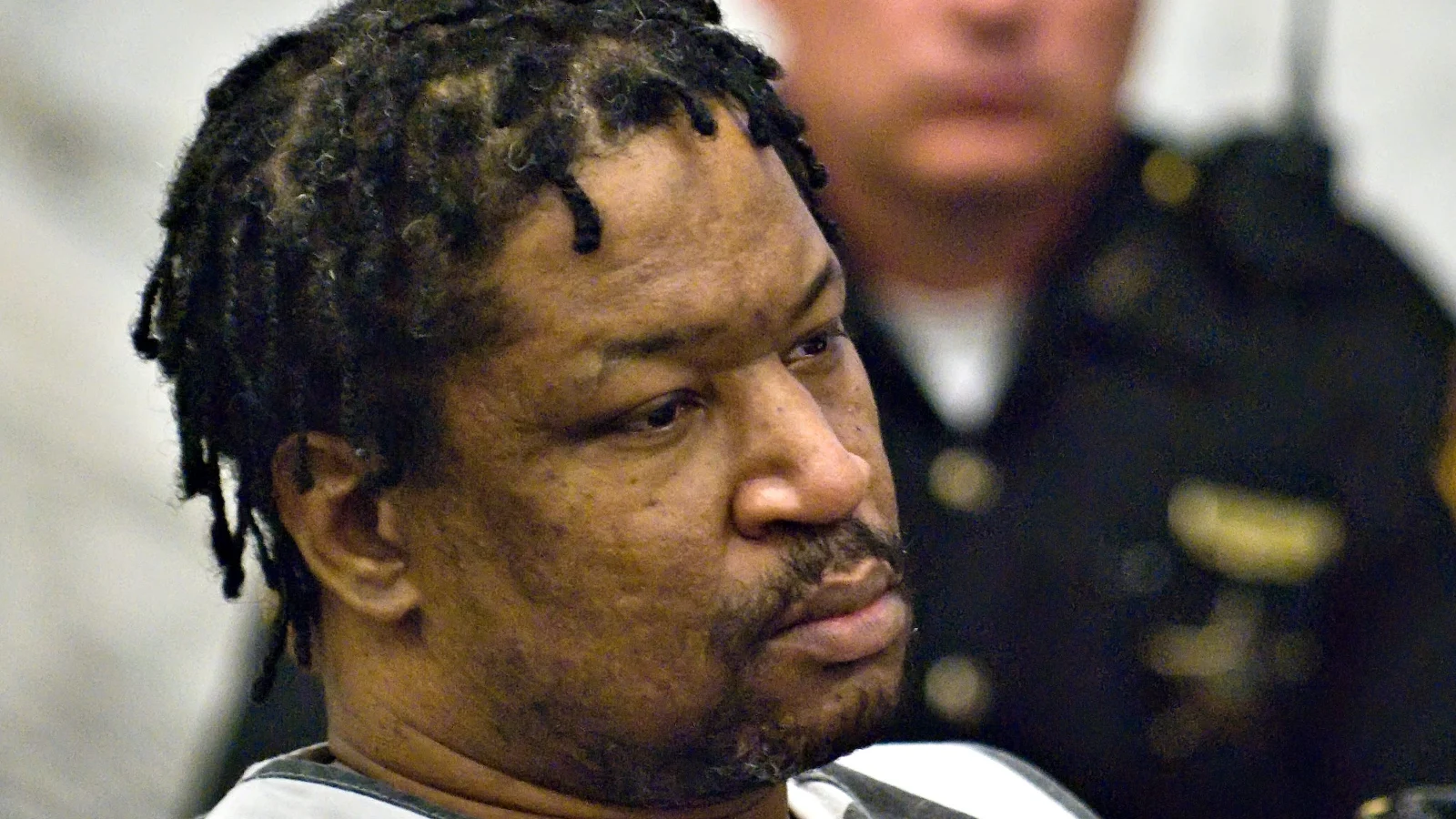 Anthony Kirkland in a striped jail uniform in a Hamilton County courtroom, a deputy behind him