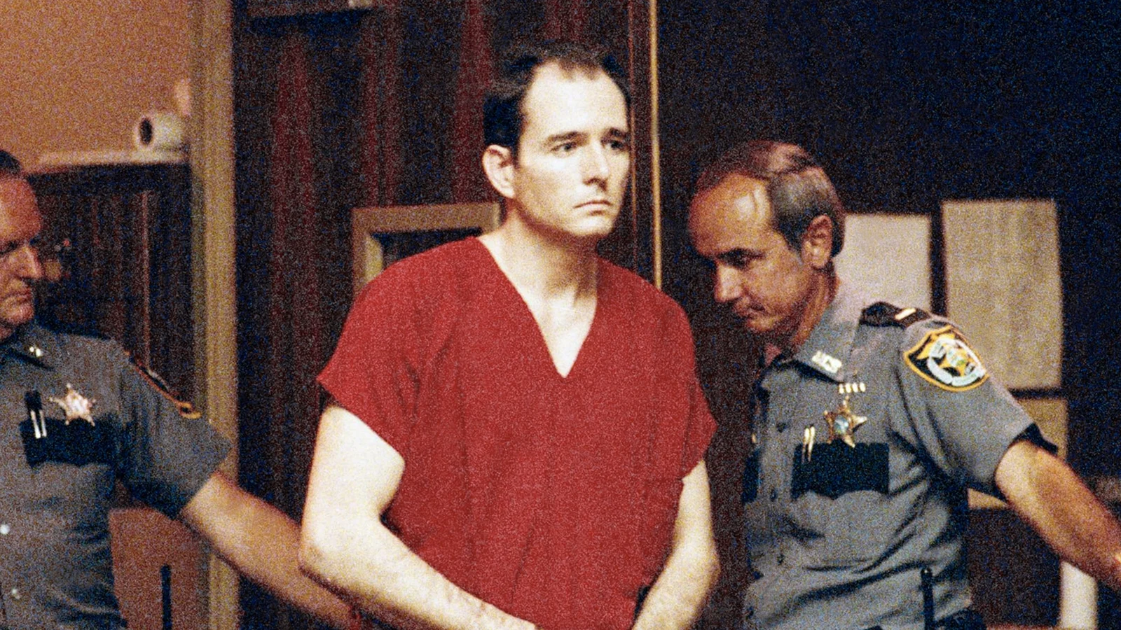 Danny Rolling in a red jail uniform, handcuffed and led by two sheriff's deputies