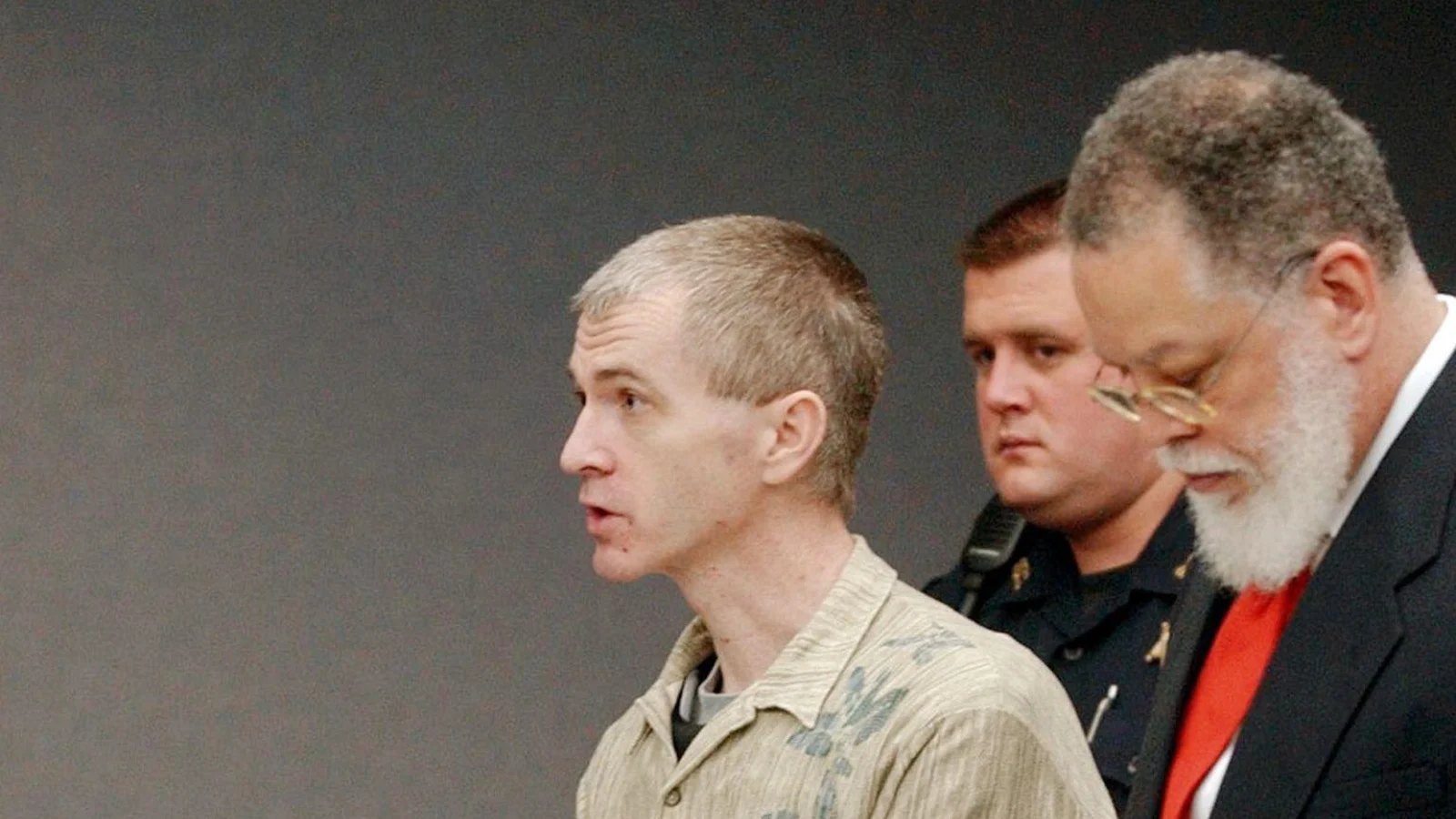 Charles Cullen, handcuffed, standing at a New Jersey courtroom table beside his lawyer and an officer