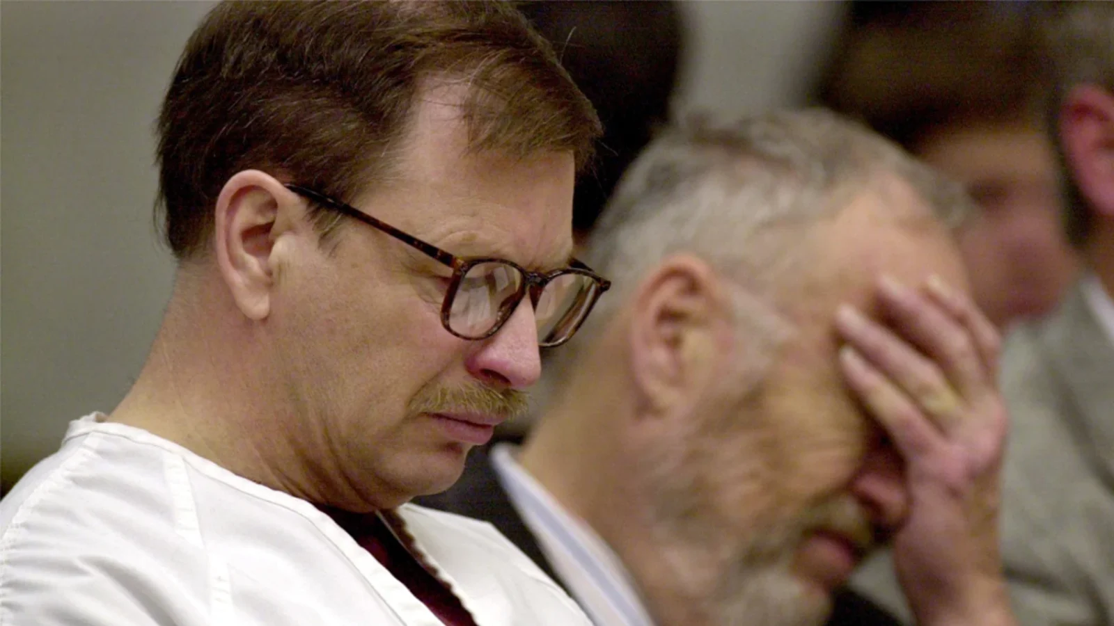 Gary Ridgway in glasses and a white jail uniform in a King County courtroom, his lawyer beside him