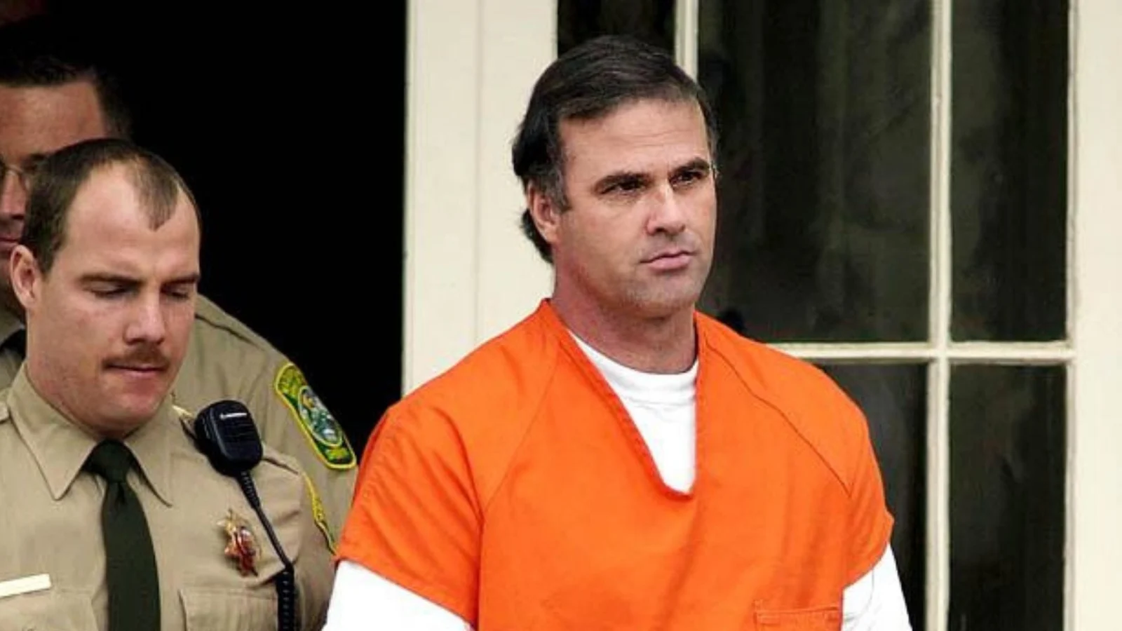 Cary Stayner in an orange jail jumpsuit, escorted from a building by a sheriff's deputy