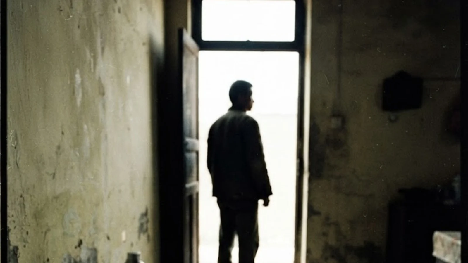 Illustration of a man seen from behind in the doorway of a bare, dim room. Not a photograph of Duan Guocheng.