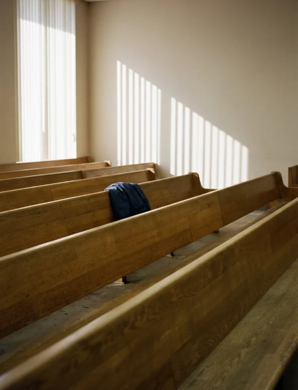 Illustration of empty courtroom gallery benches in afternoon light with a jacket left on one bench. Not an actual scene from the case.