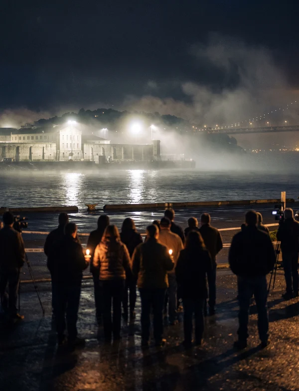 Illustration of people holding candles on a waterfront at night, facing a floodlit prison across the bay. Not an actual scene from the case.